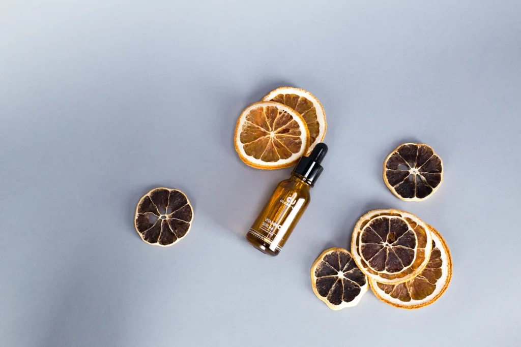Flacon de soin cosmétique entouré de tranches d'agrumes et de feuilles botaniques sur fond blanc