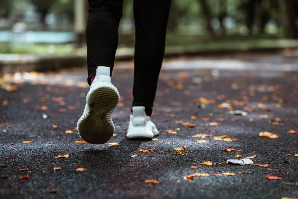 Personne en tenue de sport courant dans un parc verdoyant en lumière matinale