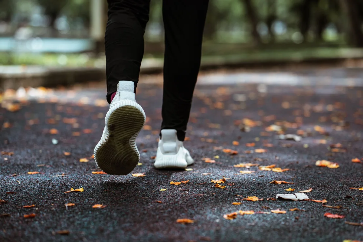 Personne en tenue de sport courant dans un parc verdoyant en lumière matinale