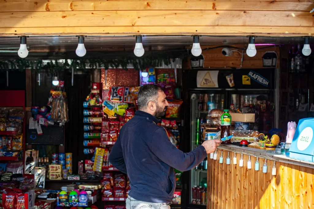 Main d'adolescent saisissant une canette de boisson énergisante colorée sur un rayon de magasin