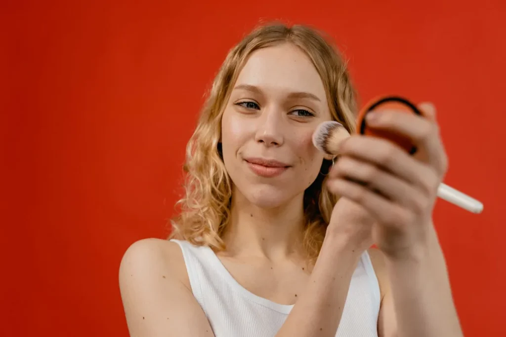 Application de bronzer à la brosse sur les pommettes et les tempes pour un teint chaud et lumineux