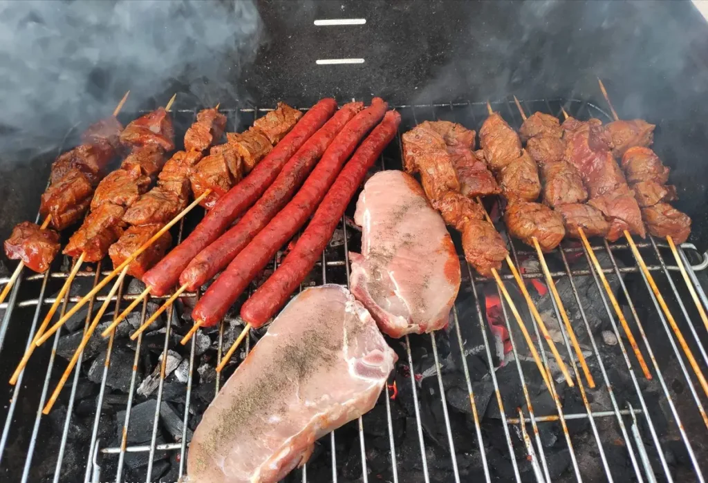 Viande en train de cuire sur un barbecue avec flammes et fumée visibles