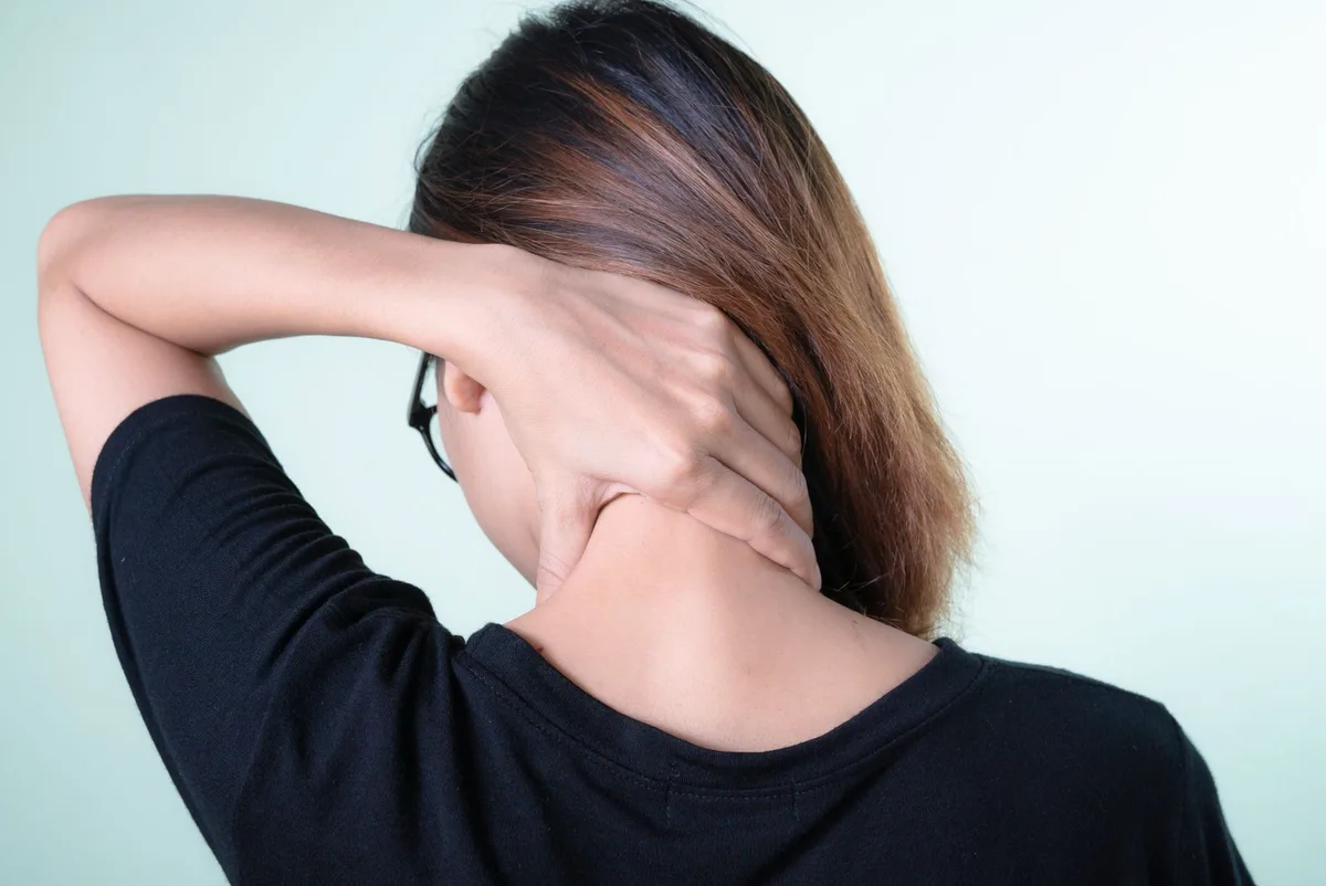 Personne assise avec les épaules contractées, montrant la tension musculaire liée au stress