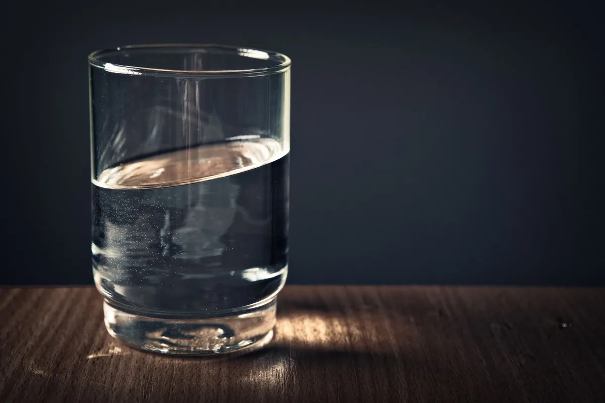 Verre d'eau avec cristaux minéraux et fruits frais symbolisant l'hydratation et les électrolytes