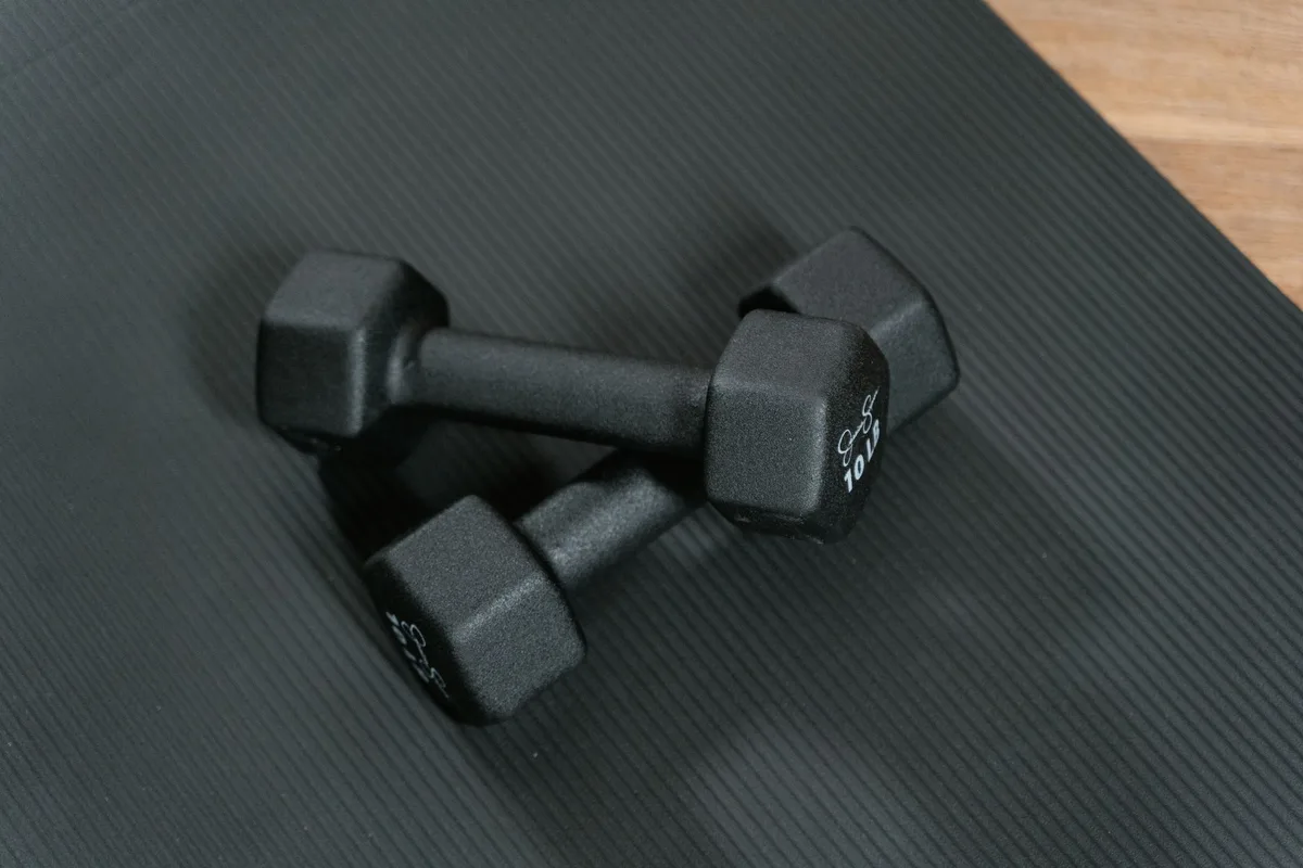 Personne effectuant un exercice de renforcement musculaire avec des poids dans une salle de sport