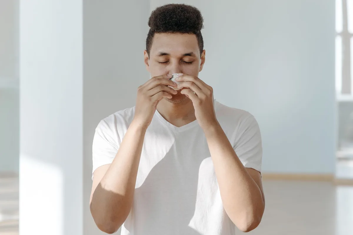 Personne toussant ou éternuant, montrant la transmission par gouttelettes respiratoires