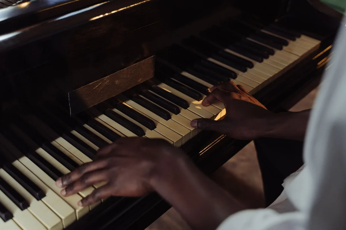 Mains d'une personne âgée posées sur les touches d'un piano avec une partition floue en arrière-plan
