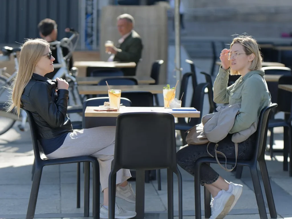 Mains saisissant des verres et des assiettes d'apéritifs sur une table de terrasse ensoleillée