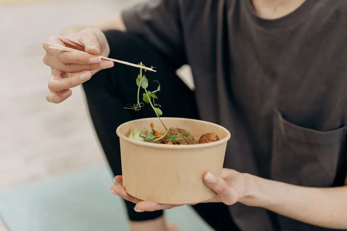 Personne préparant un repas équilibré avec des aliments frais et variés dans une cuisine lumineuse