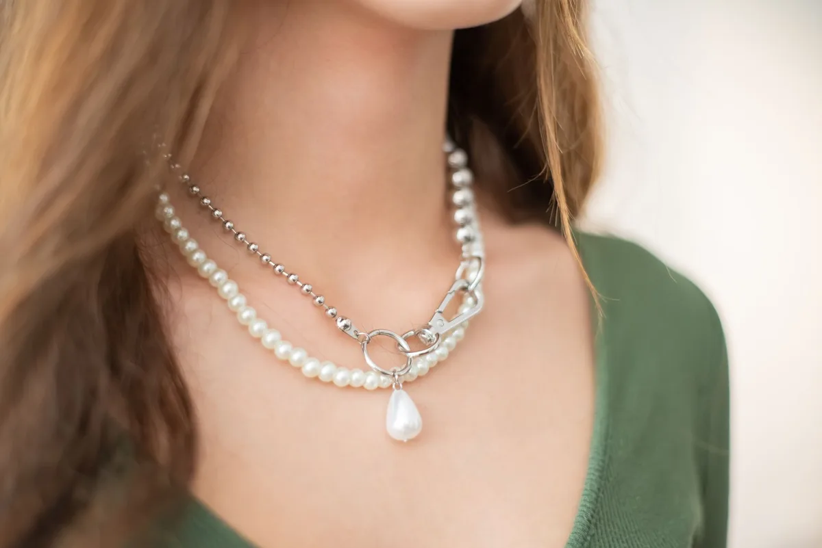 Accumulation de colliers et bijoux mélangés transformant un top simple en pièce signature