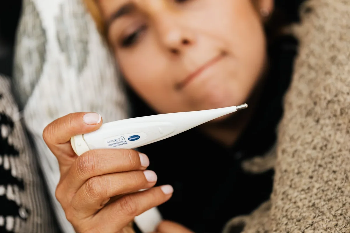 Personne mesurant sa température avec un thermomètre