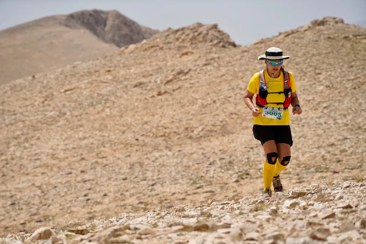 Coureur sur sentier ombragé le matin avec bouteille d'eau et équipement léger