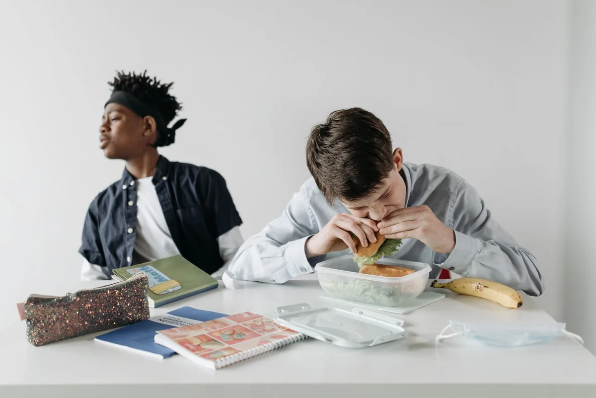 Personne stressée à son bureau tendant la main vers des aliments réconfortants