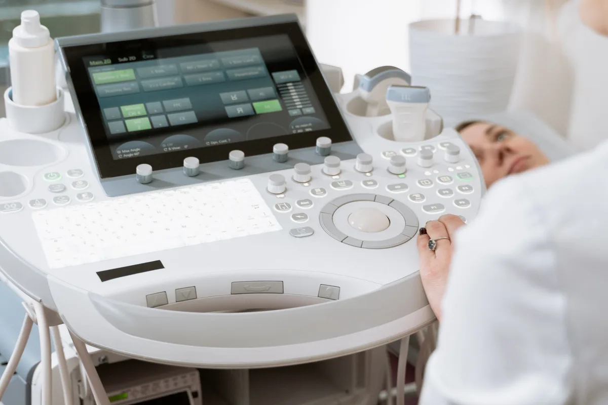 Mains d'un médecin tenant un modèle de rein avec images d'échographie et rapports médicaux sur un bureau