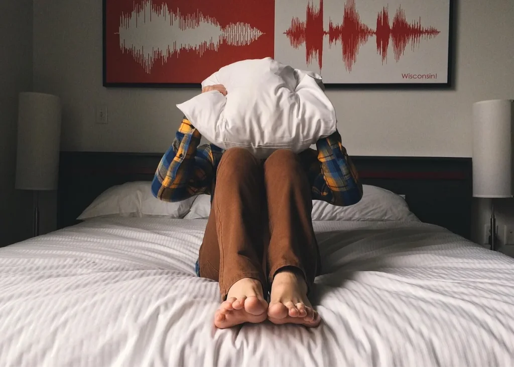 Personne assise dans son lit la nuit, réveillée et frustrée, dans une chambre sombre