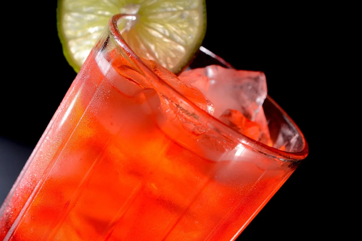 Préparation avec quartiers de citron vert, pilon et glace pilée dans un verre bas
