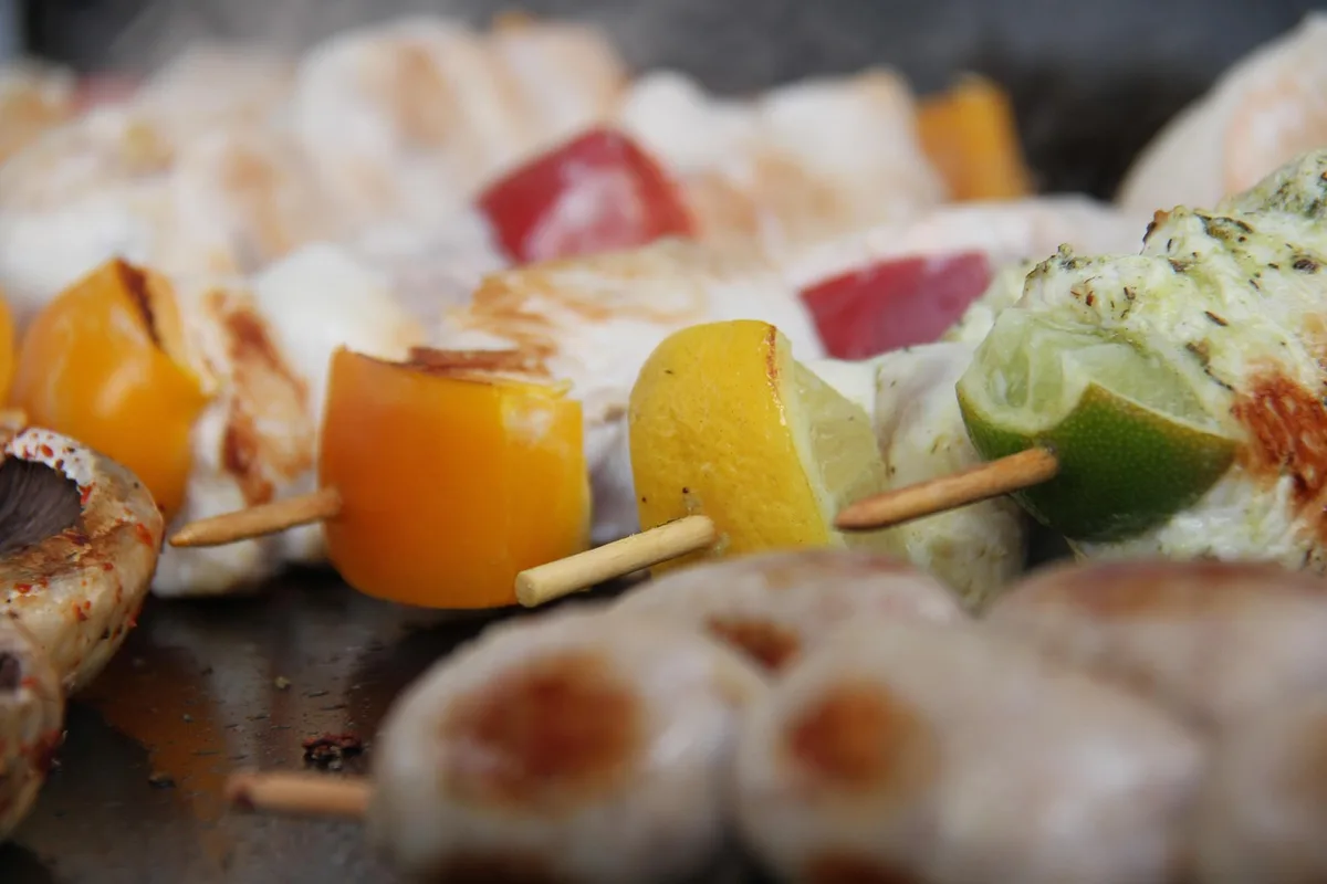 Brochettes grillées et quartier de citron vert accompagnant un verre de cocktail