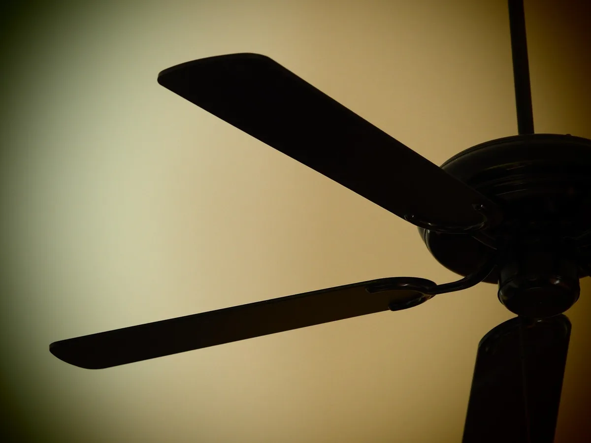 Chambre encombrée la nuit avec ventilateur indiquant sommeil perturbé par la chaleur