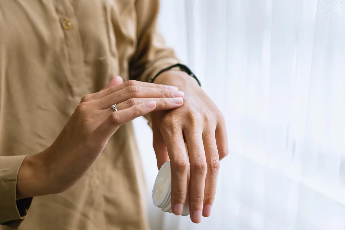 Main appliquant délicatement un soin sur la peau lors d'un test de produit beauté