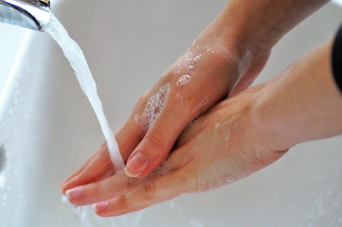 Personne se lavant les mains au lavabo, prévention des infections