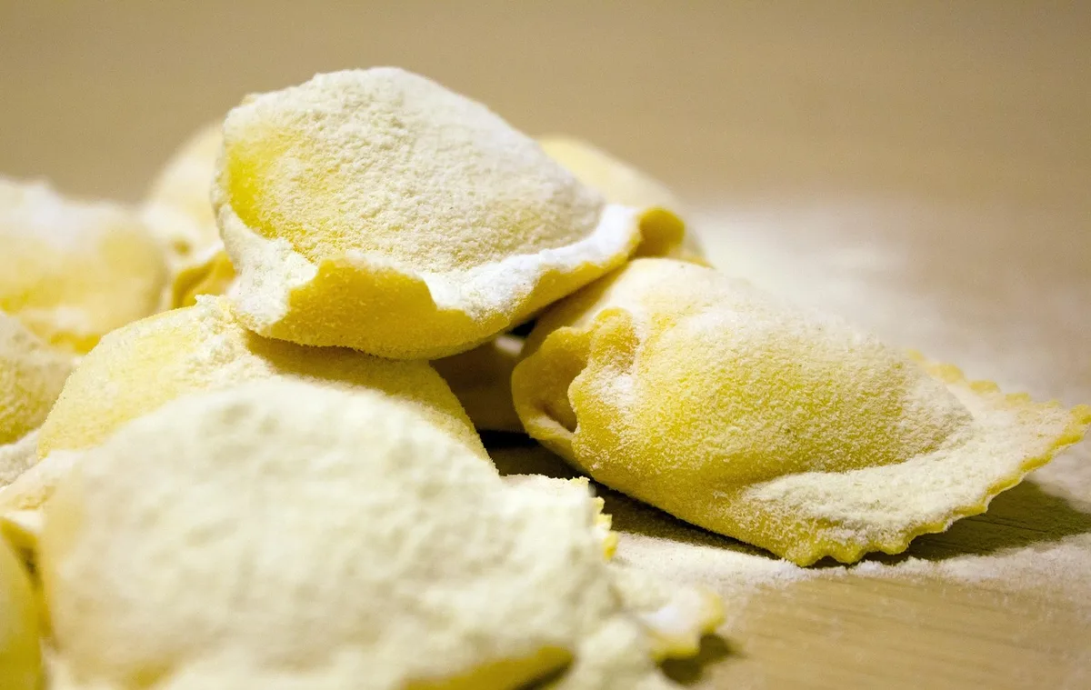 Personne égouttant des pâtes dans une passoire en cuisine lumineuse