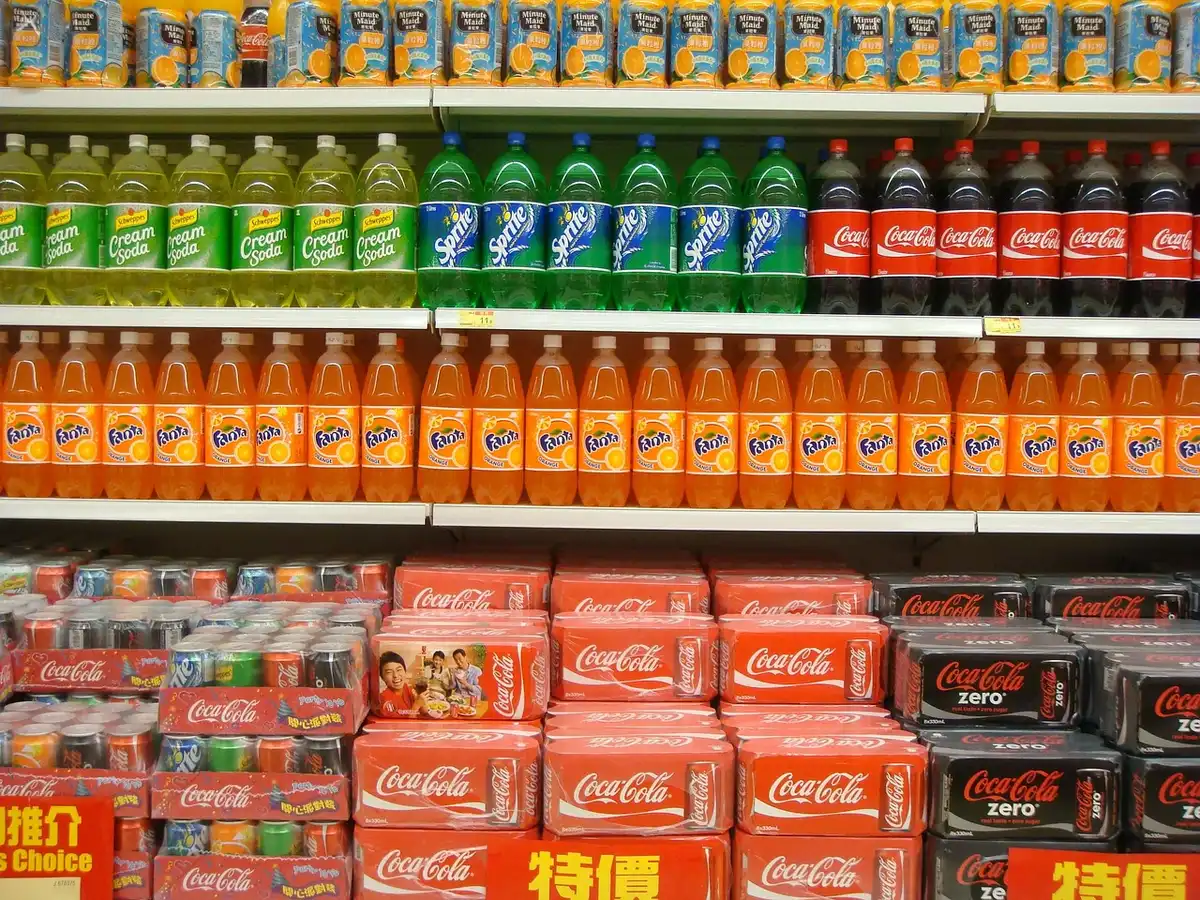Allée de supermarché avec produits étiquetés 'protéines' et main anonyme saisissant un article