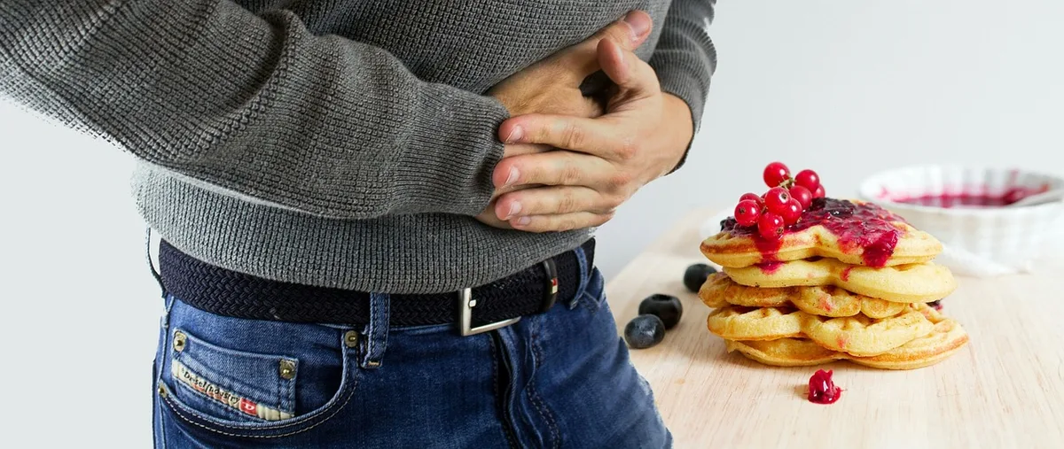 Personne fatiguée tenant son ventre, symbole de troubles digestifs et fatigue