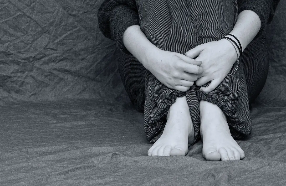 Personne anxieuse assise seule devant une assiette, illustrant l'anxiété liée à l'alimentation