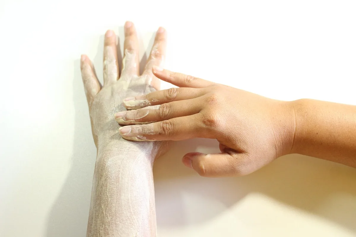 Poudre exfoliante douce versée dans la paume, texture fine et non abrasive