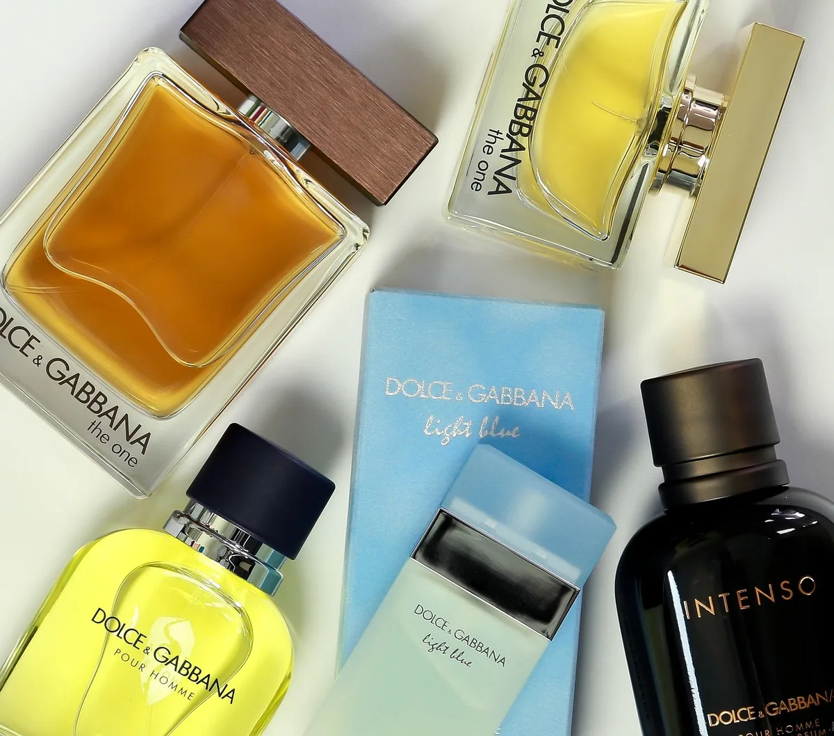 Collection de flacons de parfum aux formes et teintes variées sur une surface neutre, éclairage naturel doux