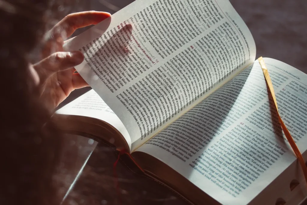 Silhouette de dos cherchant un mot, devant des livres et objets flous
