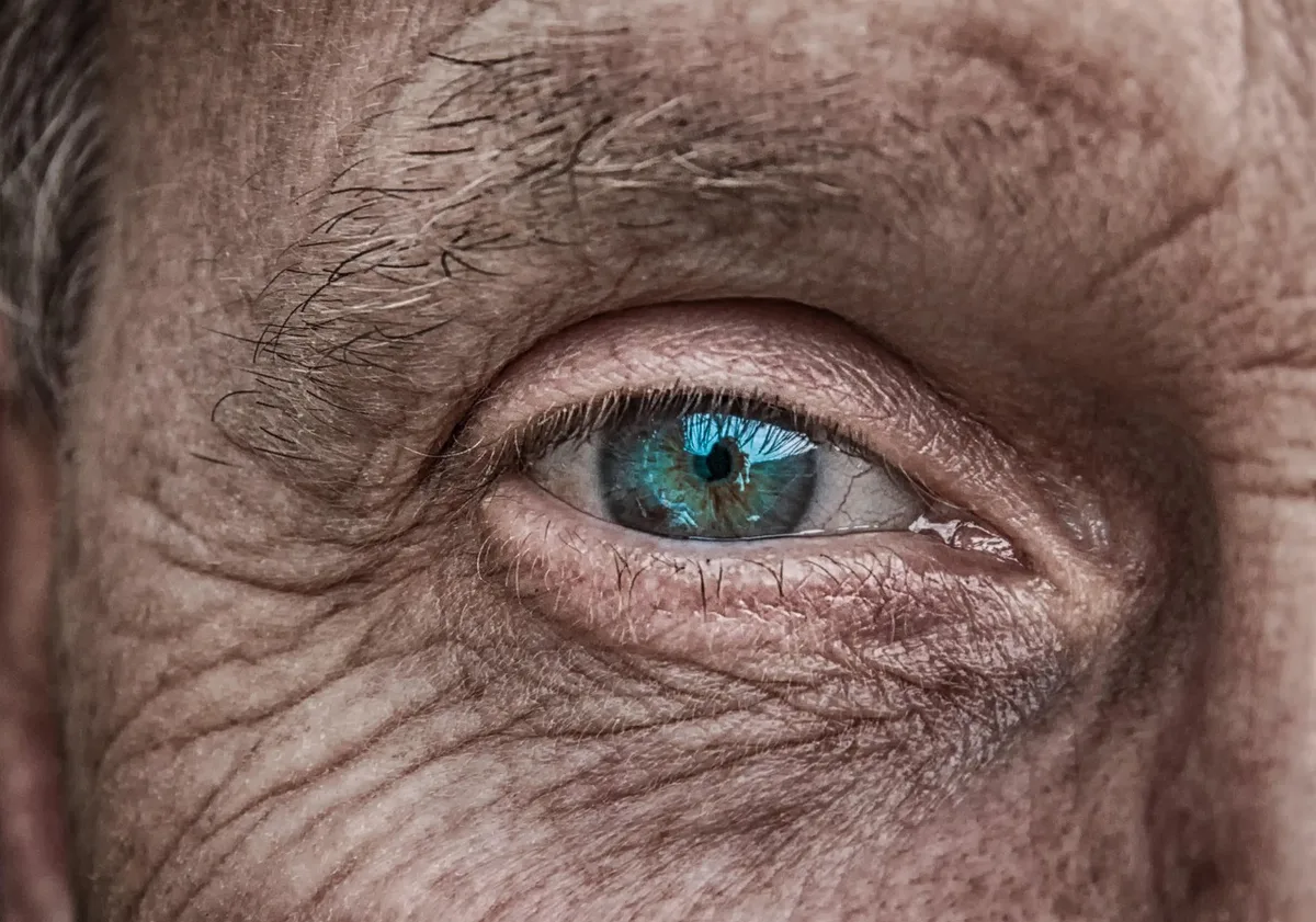 Femme les yeux fermés, main sur la tempe, lumière naturelle douce