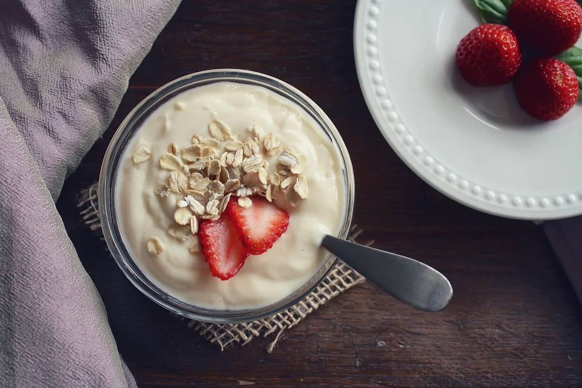 Yaourt nature avec compote de fraises maison versée à côté