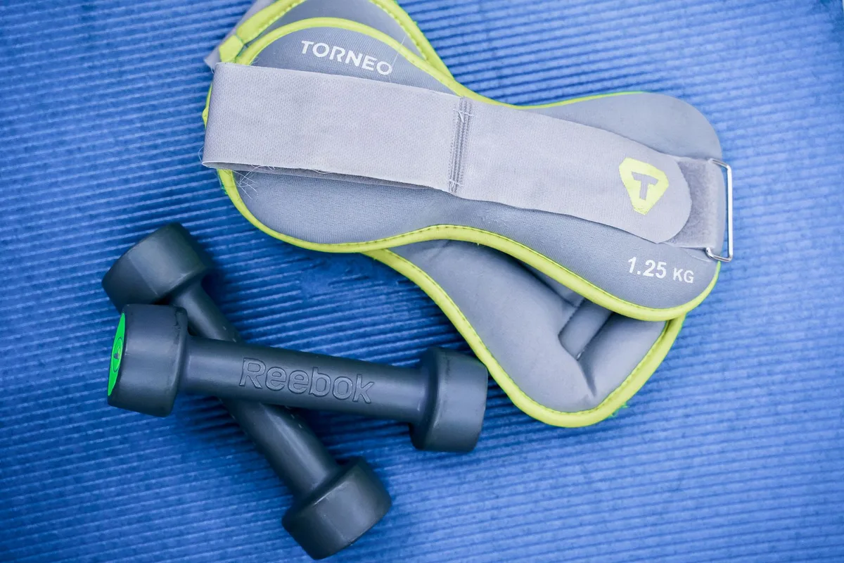 Personne anonyme faisant des exercices de renforcement avec haltères légers