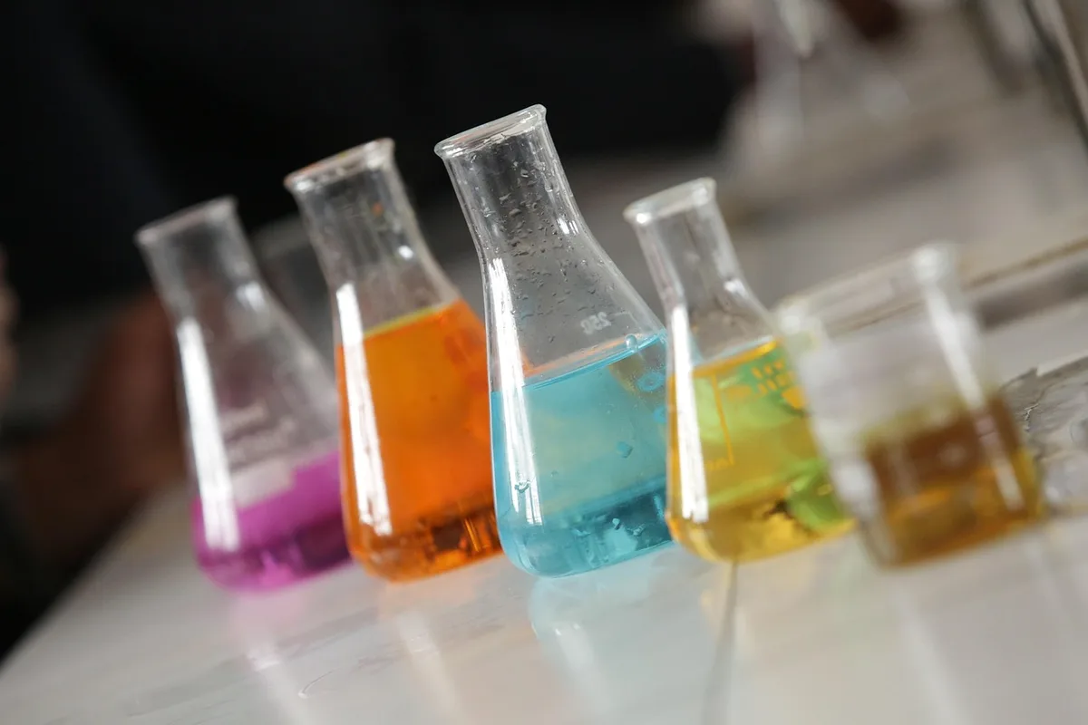 Laboratoire en journée, mains gantées manipulant une lame de microscope près d'une table ensoleillée