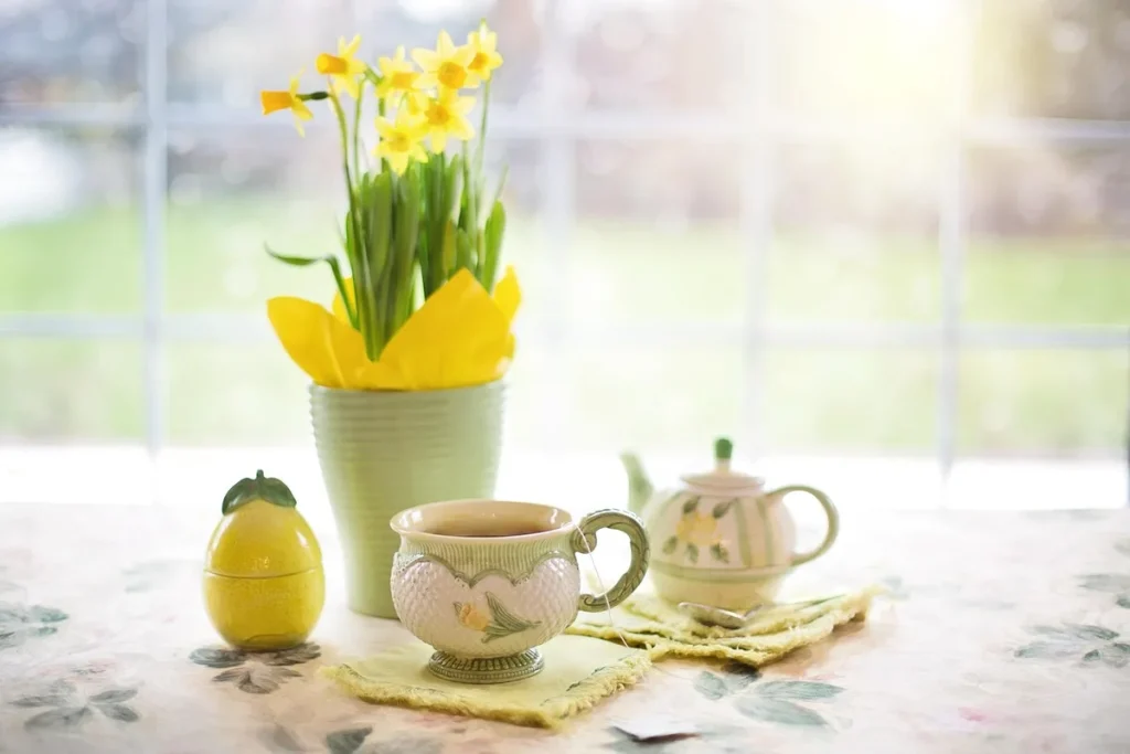 Table de cuisine en pleine journée, mug chaud et agenda ouvert près d'une paire de chaussures floue