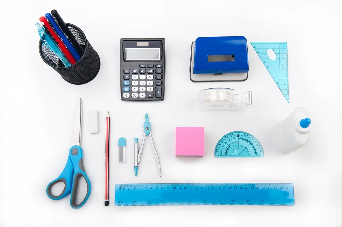 Table de cuisine en plein jour avec calculatrice, carnet et mètre ruban, mains anonymes saisissant des chiffres