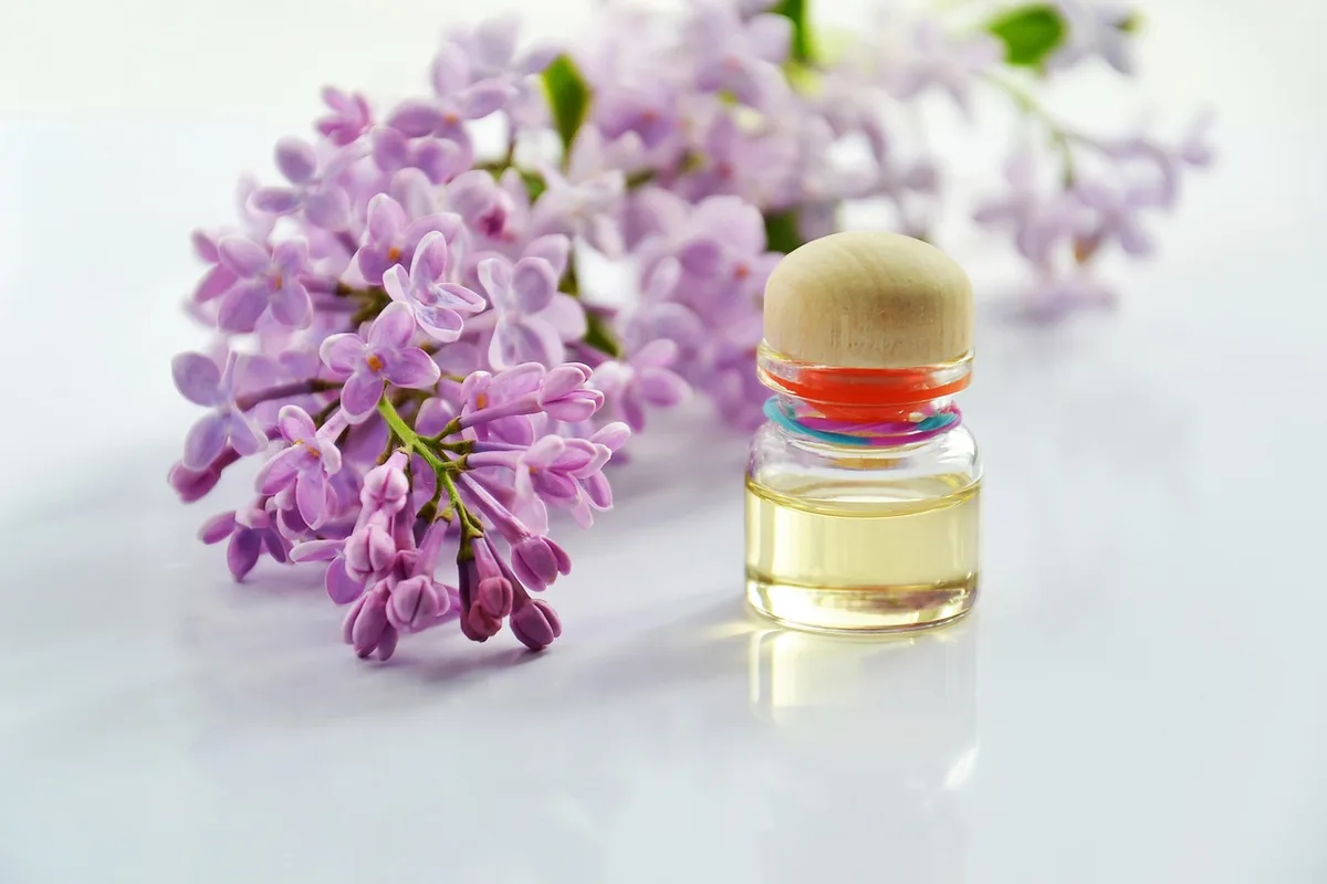 Personne effectuant un massage facial avec produits de soin près d'une fenêtre en journée