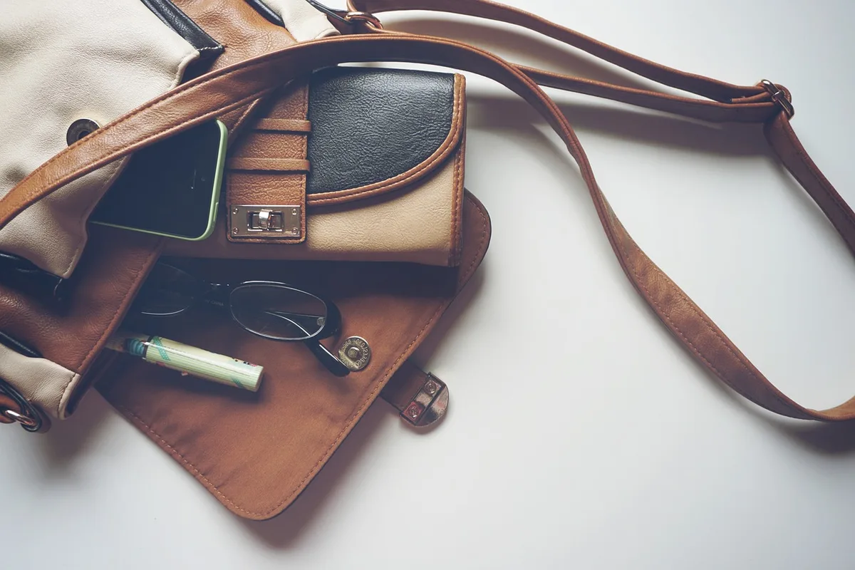 Sac bandoulière en cuir et bijoux minimalistes posés sur une table