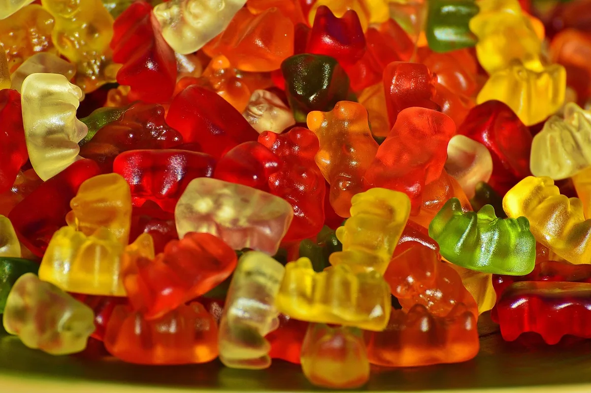 Bocal de gummies pour cheveux posé sur une table lumineuse près d'un carnet et d'une tasse