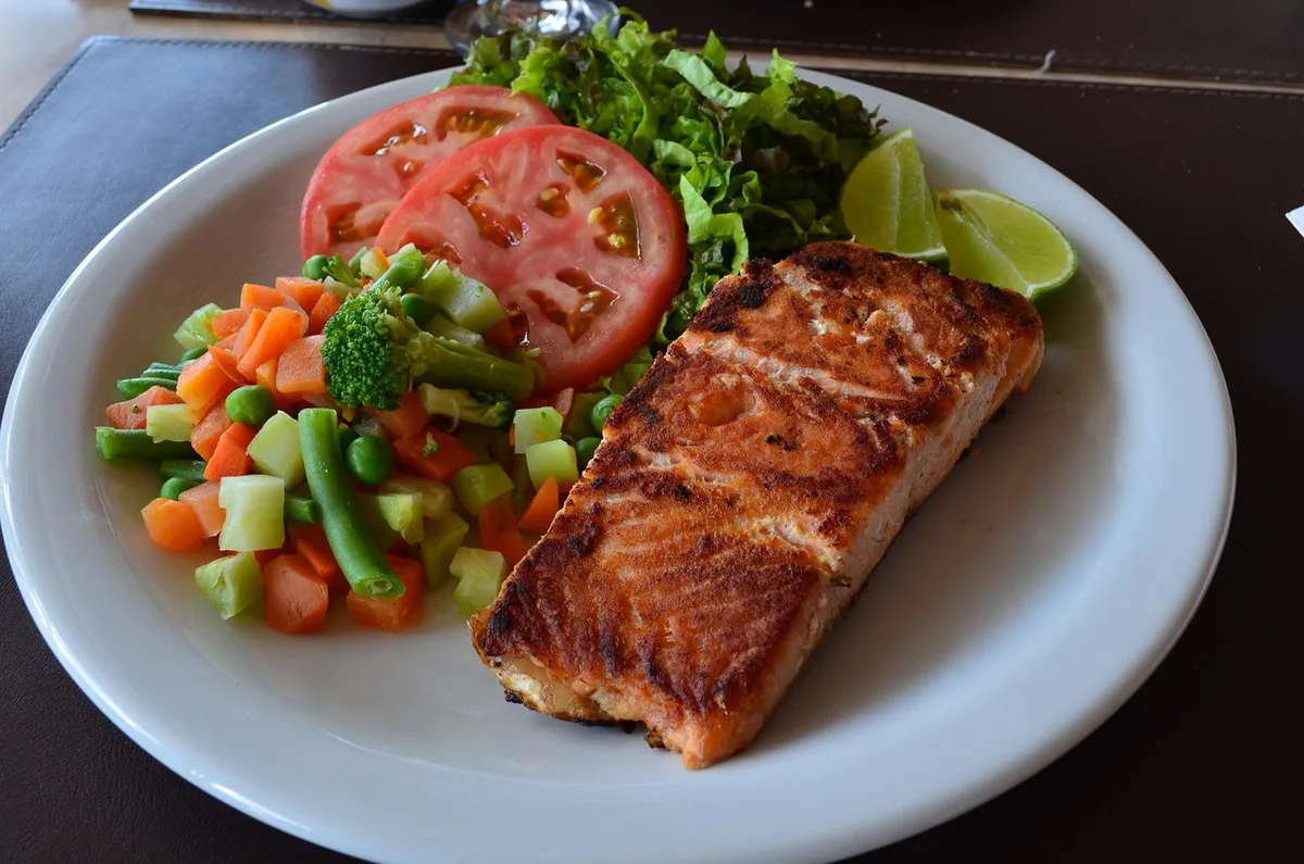 Plat cuit à la vapeur et poisson grillé sur une assiette, près d'un menu