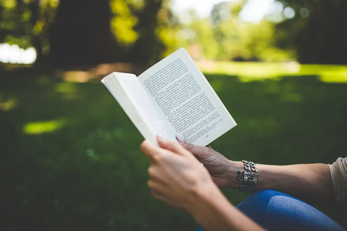 Table de chevet avec livre ouvert près d'une fenêtre lumineuse